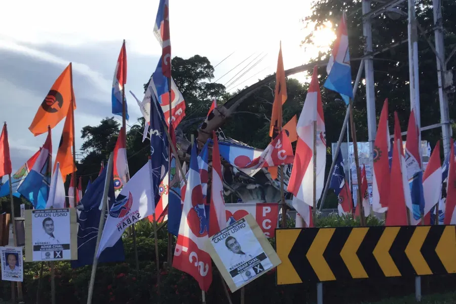 flags of different colours hanged on poles in disarray by the street